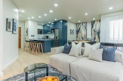 a living room with a couch and a kitchen at Modern Central 1 BR Apartment in Stellenbosch
