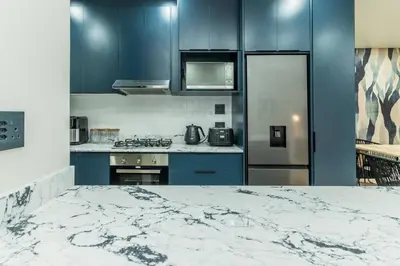 a kitchen with blue cabinets and a refrigerator at Modern Central 1 BR Apartment in Stellenbosch