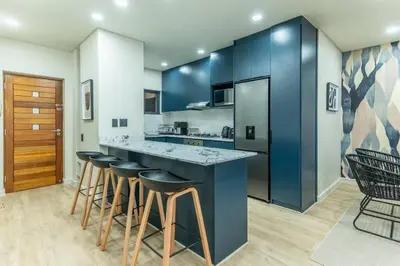 a kitchen with blue cabinets and bar stools at Modern Central 1 BR Apartment in Stellenbosch
