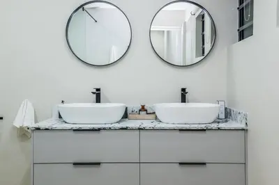 a bathroom with two sinks and a mirror at Modern Central 1 BR Apartment in Stellenbosch