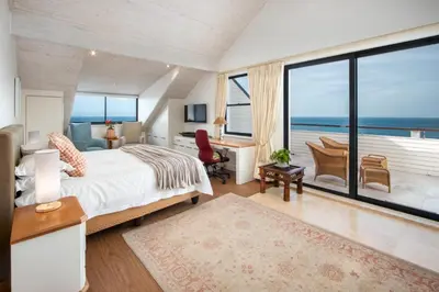 a bedroom with a bed and a view of the ocean at Hermanus Luxury Penthouse in Hermanus