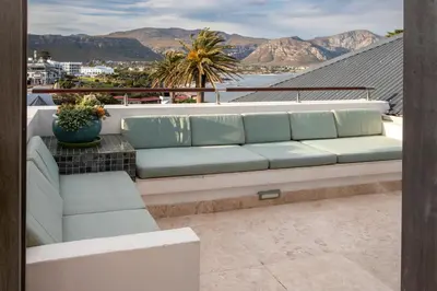 a couch on a balcony with mountains in the background at Hermanus Luxury Penthouse in Hermanus