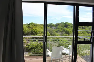 two white chairs sitting on a deck looking out the window at 17 Suikerbossie in Hermanus