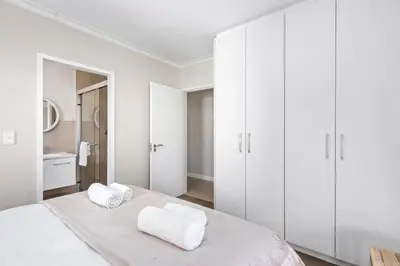 a white bedroom with white cabinets and a bed at Mayfair 246 by Host Agents in Cape Town