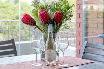 a table with two glasses and a bottle of wine and flowers at Mayfair 246 by Host Agents in Cape Town