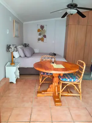 a living room with a table and a bed at The High Street Accommodation in Durbanville