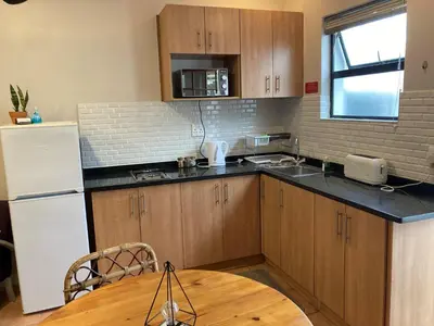 a kitchen with wooden cabinets and a white refrigerator at The High Street Accommodation in Durbanville