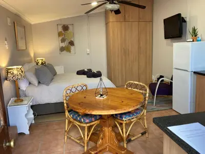 a kitchen and a living room with a table and a couch at The High Street Accommodation in Durbanville