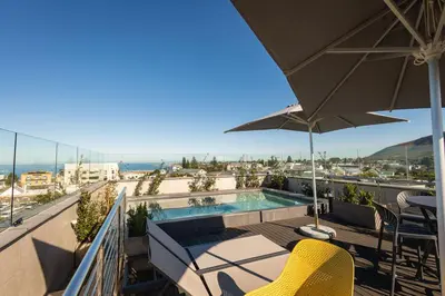 a balcony with a swimming pool and an umbrella at Sea-View Studio - Hermanus Waterfront Apartments in Hermanus