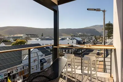 a balcony with chairs and a view of a city at Sea-View Studio - Hermanus Waterfront Apartments in Hermanus