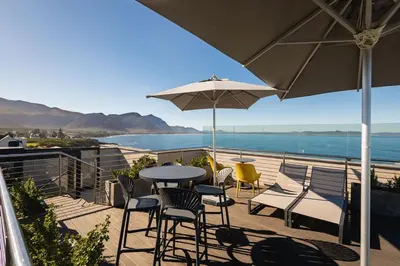a patio with a table and chairs and an umbrella at Sea-View Studio - Hermanus Waterfront Apartments in Hermanus