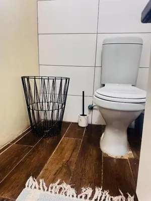 a bathroom with a white toilet and a wooden floor at Greens Haven, Your Private escape in Cape Town in Cape Town