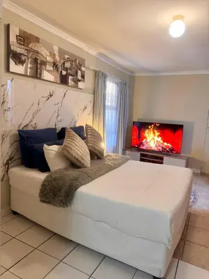 a bedroom with a large white bed and a fireplace at Greens Haven, Your Private escape in Cape Town in Cape Town