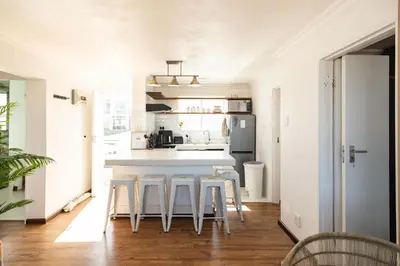 a kitchen with a white counter and stools at Coastal Living in Hermanus
