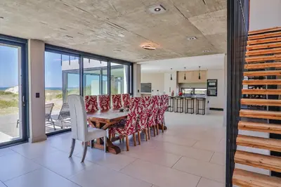a dining room with a table and chairs at The Dunes in Bettyʼs Bay