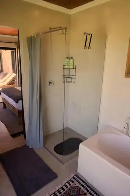 a bathroom with a shower with a tub and a sink at Cozy House & Studio with Sea and Mountain Views in Bettyʼs Bay