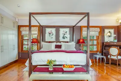 a bedroom with a canopy bed with a bowl of fruit on a table at Franschhoek Manor in Franschhoek