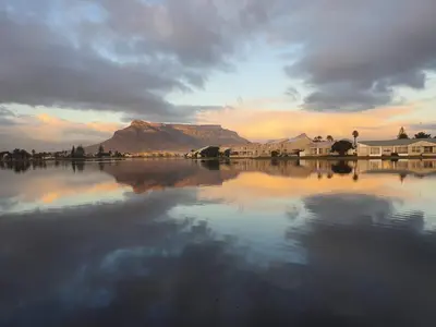 a view of a mountain from the water at sunset at Woodbridge Lodge in Cape Town