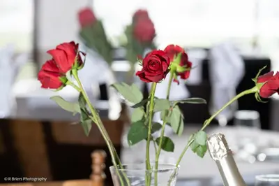 a vase filled with red roses on a table at Woodbridge Lodge in Cape Town