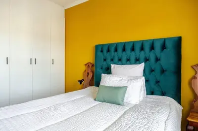 a bedroom with a large bed with a blue headboard at Affordable Luxury in Cape Town