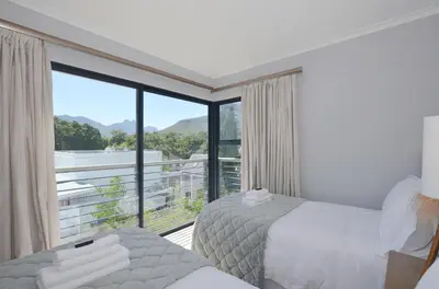a bedroom with two beds and a large window at Church View Lux Apartment in Stellenbosch