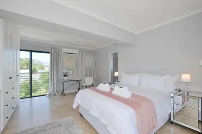 a white bedroom with a large bed with towels on it at Church View Lux Apartment in Stellenbosch