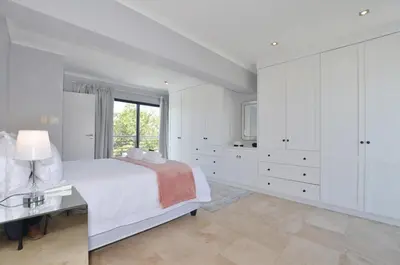 a white bedroom with a large bed and a window at Church View Lux Apartment in Stellenbosch
