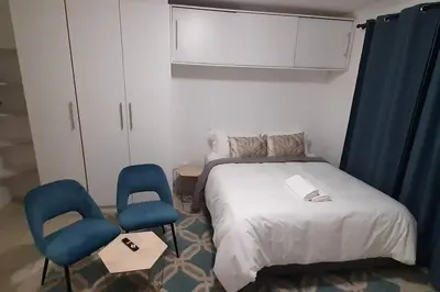 a bedroom with a bed and two blue chairs at Convenient Comfort in Cape Town