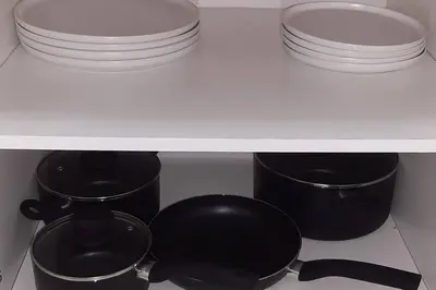 a shelf with plates and pots and pans in a kitchen at Convenient Comfort in Cape Town