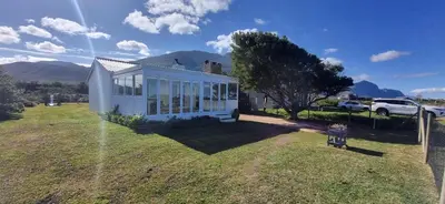 a small white house on a grassy field at 4859 Lakeside in Bettyʼs Bay