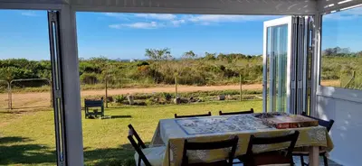 a table and chairs on a porch with a view of a field at 4859 Lakeside in Bettyʼs Bay