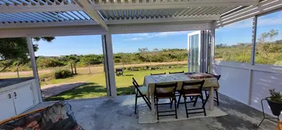 a screened in porch with a table and chairs at 4859 Lakeside in Bettyʼs Bay