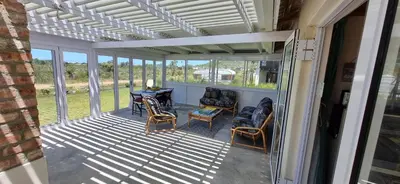 a screened in porch with a table and chairs at 4859 Lakeside in Bettyʼs Bay