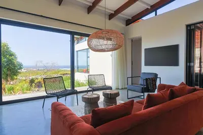 a living room with a couch and chairs and a television at BonAir Betty's Bay in Bettyʼs Bay