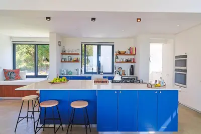 a kitchen with blue cabinets and bar stools at BonAir Betty's Bay in Bettyʼs Bay