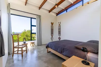 a bedroom with a bed and a large window at BonAir Betty's Bay in Bettyʼs Bay