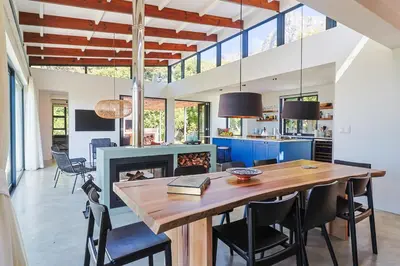 a kitchen and dining room with a table and a fireplace at BonAir Betty's Bay in Bettyʼs Bay