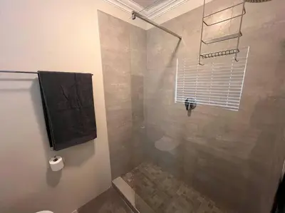 a bathroom with a shower with a toilet and a window at #Spacious Cozy Stay- Free parking in Stellenbosch
