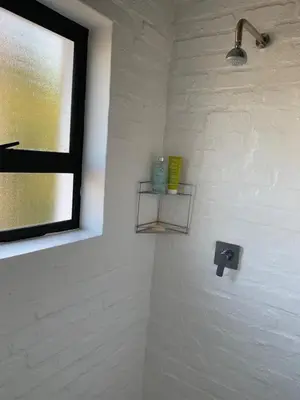 a bathroom with a sink with a window and a shelf at Two Palms Cottage in Hermanus