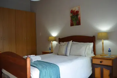 a bedroom with a large bed with two night stands at Winecellar Cave, on wine farm & where lions roar! in Stellenbosch
