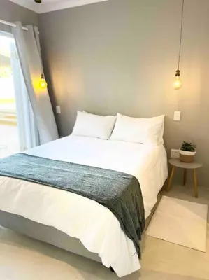 a bedroom with a large white bed and a table at Amazing Brand New Holiday Home with Pool! in Hermanus