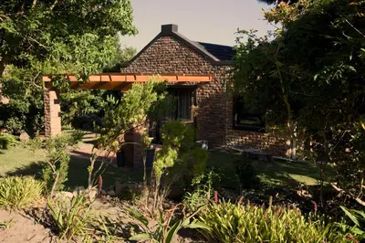 a brick house with awning in a garden at Fynbos Cottage with Sea View - Self-catering in Bettyʼs Bay