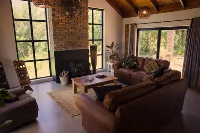 a living room with leather furniture and a fireplace at Cozy House with Sea and Mountain Views in Bettyʼs Bay