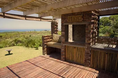 a brick patio with a bench and a fireplace at Cozy House with Sea and Mountain Views in Bettyʼs Bay