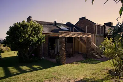 a brick house with a patio and a tree at Cozy House with Sea and Mountain Views in Bettyʼs Bay