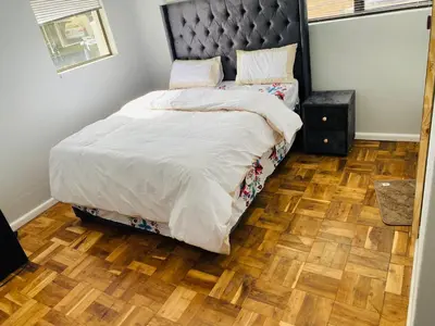 a bedroom with a bed and a wooden floor at 22clyde street bostin in Cape Town