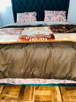 a bed with a brown comforter and pillows on it at 22clyde street bostin in Cape Town
