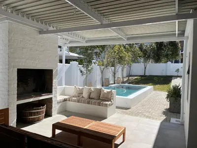 a patio with a couch and a fireplace and a pool at Bikini House - With Pool in Hermanus