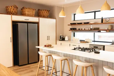 a kitchen with a white counter and stools at Bikini House - With Pool in Hermanus