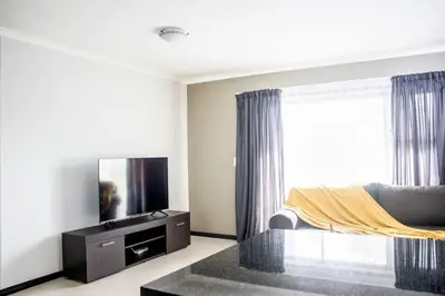 a living room with a couch and a flat screen tv at 7 on Laibach - Buhrein Estate, Kraaifontein in Cape Town